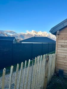 a fence in front of a house with mountains in the background at Gîte du Moulin- CLG Savoie - Vélo tourisme - 3CH - 2SDB 