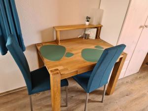 a wooden table with two blue chairs around it at Ferienwohnung ZWEI nähe Büsum in Oesterdeichstrich