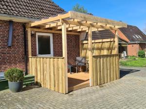 a wooden pergola with a chair on a patio at Ferienwohnung ZWEI nähe Büsum in Oesterdeichstrich