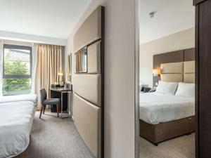 a hotel room with two beds and a desk at Mercure Edinburgh Haymarket in Edinburgh