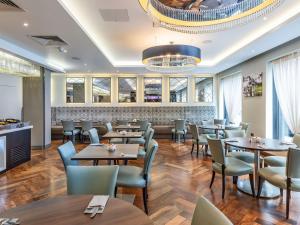 uma sala de jantar com mesas e cadeiras e um lustre em Mercure Edinburgh Haymarket em Edinburgo