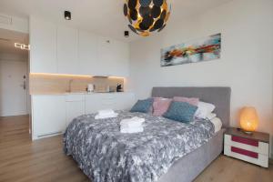 a bedroom with a large bed and a kitchen at Apartament Deluxe Sea View PINEA 606 in Pobierowo