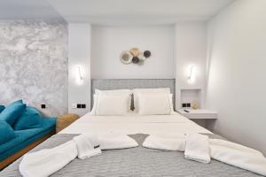 a white bedroom with a large bed and a blue couch at Sapphire Kythnos Suites in Mérikhas