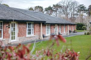 a brick house with benches in a yard at Finest Retreats - Netley Hall - Poppy in Dorrington