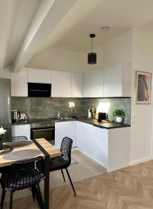 パライユ・ヴィエイユ・ポストにあるMagnifique Appartement Neuf, 5 Min Orly - Climatiséの白いキャビネット、テーブルと椅子付きのキッチンが備わります。
