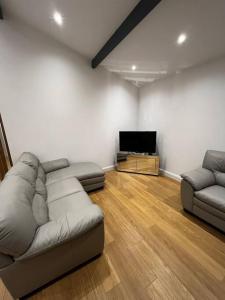 uma sala de estar com 2 sofás e uma televisão de ecrã plano em The Forest Haven Cottage - Free Parking & Wi-Fi em Whitefield