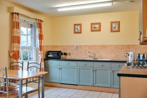 a kitchen with blue cabinets and a sink and a table at Finest Retreats - Netley Hall - Mulberry in Dorrington