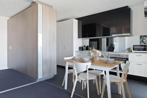 a kitchen with a wooden table and white chairs at A Modern 2BR Apt with Harbour Views FREE Parking in Melbourne