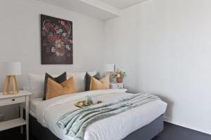 a bedroom with a large white bed with orange pillows at A Modern 2BR Apt with Harbour Views FREE Parking in Melbourne