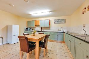 Dorrington的住宿－Finest Retreats - Netley Hall - Peach Tree，厨房配有木桌和白色冰箱。
