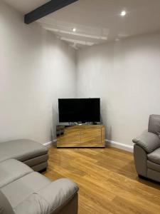 uma sala de estar com 2 sofás e uma televisão de ecrã plano em The Forest Haven Cottage - Free Parking & Wi-Fi em Whitefield