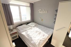 ein Schlafzimmer mit einem weißen Bett in einem Zimmer mit einem Fenster in der Unterkunft Frische Brise 10.02 in Cuxhaven
