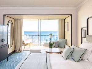 カンヌにあるMondrian Cannesのベッドと大きな窓が備わるホテルルームです。