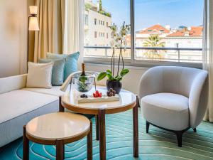 un soggiorno con divano, tavolo e sedia di Mondrian Cannes a Cannes