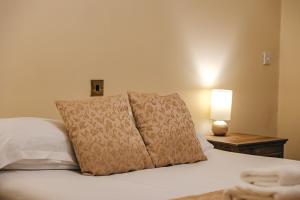 ein Bett mit zwei Kissen und einer Lampe auf einem Tisch in der Unterkunft Finest Retreats - Netley Hall - Lavender in Dorrington