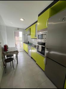 a kitchen with yellow and green cabinets and a table at La oliva in Cáceres