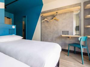 - une chambre avec un lit et un mur bleu dans l'établissement ibis Budget La Rochelle Centre, à La Rochelle