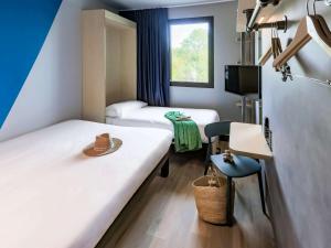 a hotel room with two beds and a window at ibis Budget La Rochelle Centre in La Rochelle