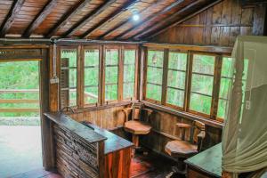 eine Hütte mit Fenstern, einem Tisch und Bänken in der Unterkunft Omah kayu bromo in Ngadisari