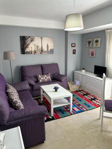 a living room with purple couches and a table at Apartamento La Iglesia in Almodóvar del Río