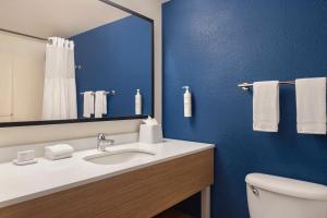 a bathroom with a sink and a mirror and a toilet at Spark by Hilton Orlando Universal Blvd in Orlando