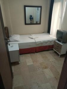 um pequeno quarto com uma cama e uma televisão em Blue otel çeşme em Cesme