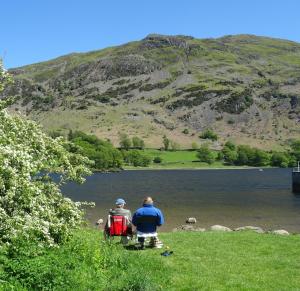 two people sitting on a bench near a lake at Kents Bank Holiday - Pet Friendly with Bay Views in Grange Over Sands