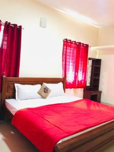 Schlafzimmer mit roten Vorhängen und einem großen Bett in der Unterkunft NABA HOME STAY OOTY in Udagamandalam