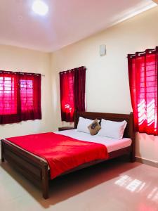 Schlafzimmer mit roten Vorhängen und einem Bett mit roter Bettwäsche in der Unterkunft NABA HOME STAY OOTY in Udagamandalam