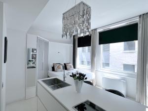 a white kitchen with a sink and a chandelier at The Boutique Houses Milan - Galleria - With Private Parking in Milan