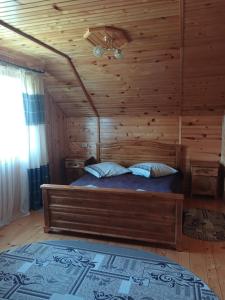 1 dormitorio con 1 cama con pared de madera en На Пагорбі, en Mykulychyn