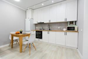 cocina con armarios blancos y mesa de madera en Уютная двухкомнатная квартира в центре города, en Kokshetau