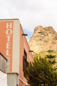 a building with a sign in front of a mountain at Tamahuche Hotel Rural in Vallehermoso