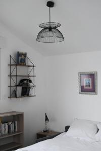 een slaapkamer met een bed en een hanglamp bij GuestReady - Monochromatique near the port in La Rochelle