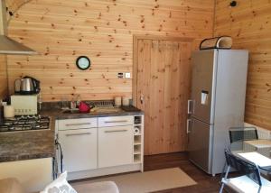 a kitchen with wooden walls and a refrigerator at Herons Lake Retreat in Caerwys