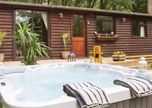 a hot tub on a deck with a cabin at Herons Lake Retreat in Caerwys