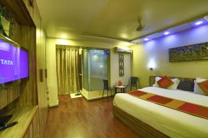a hotel room with a bed and a flat screen tv at Shaleen Elegance Homestay Near Nakki Lake in Mount Ābu
