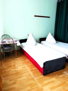 two beds in a room with a table and a chair at Hostel Omega in Rzeszów