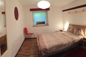 1 dormitorio con cama, ventana y silla roja en Large 8 Bed Apartment. Perfect Location., en Stuhlfelden