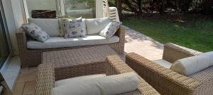 two wicker chairs and a couch on a patio at Maison classée 2*, 6 personnes, animal accepté, mer 300m in Soulac-sur-Mer