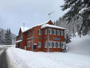 un gran edificio de ladrillo con nieve en el suelo en Apartmán Horalka 7 v Peci pod Sněžkou, en Pec pod Sněžkou