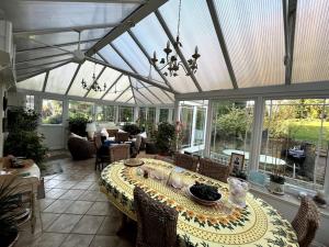 a conservatory with a table in a room with windows at Spacious 4 bed family home near coast in North Creake