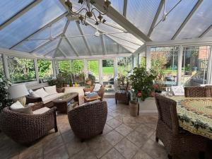 a conservatory with a glass roof with furniture and windows at Spacious 4 bed family home near coast in North Creake