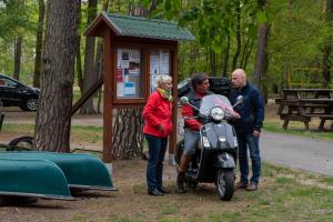 un grupo de personas de pie junto a una motocicleta en un parque en Knatter(ferien)häuschen, en Bantikow