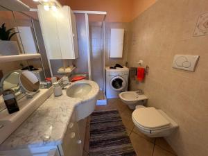 a bathroom with a sink and a toilet and a washing machine at Miralago in Stresa