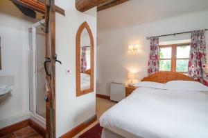 a bedroom with a white bed and a mirror at Mill Cottage in Buckinghamshire
