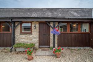 una casa con una puerta de madera y dos macetas de flores en Mill Cottage, en Buckinghamshire