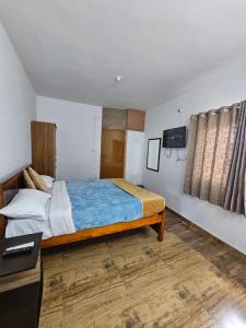 a bedroom with a bed and a desk and a television at Happy Home Stay in Ooty
