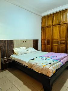 a bed in a bedroom with wooden cabinets at Résidence D in Bafoussam