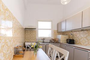 a kitchen with white cabinets and a wooden table at Syros DouBleTS Apartments in Ermoupoli